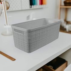 a gray basket sitting on top of a white table