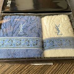 two bath towels in a clear box on a wooden table next to a cell phone