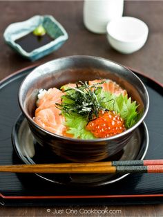 a bowl of sushi and chopsticks on a plate