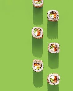 four sushi rolls are arranged on a green surface