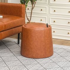 a living room with a brown leather chair and footstool in front of a white dresser