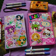 various stationery items laid out on a purple and white checkered tablecloth with markers, pens, pencils, and an eraser