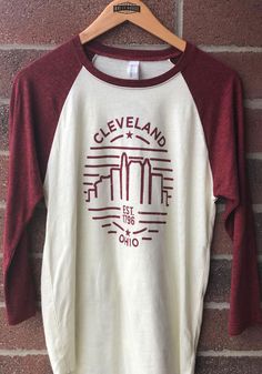 Cleveland Cream Skyline Raglan 3/4 Sleeve Triblend Shirt - 8810016 Heather Crew Neck Top With Graphic Print, Graphic Tee With Screen Print And Raglan Sleeves, College Raglan Sleeve T-shirt With Graphic Print, Sporty Graphic Print T-shirt With Raglan Sleeves, Tri-blend Graphic Tee Made In Usa, Cleveland Browns Shirts, Raglan Tee, Raglan Shirts, Cleveland Browns