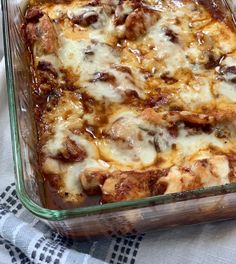 a casserole dish with meat and cheese in it sitting on a tablecloth