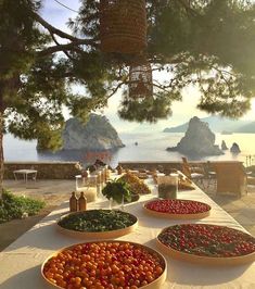 several bowls filled with different types of fruits and vegetables on a table near the ocean