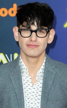 a man with glasses and a suit jacket on posing for the camera at an event