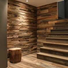 an empty room with wooden walls and steps leading up to the second floor, along with a stool