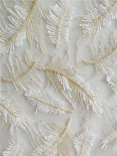 white and gold embroidered fabric with leaves on it