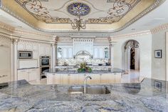 a large kitchen with marble counter tops and an ornate design on the ceiling over the sink