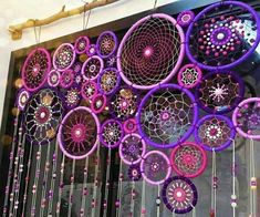 purple and pink dream catchers are hanging on the wall in front of a window