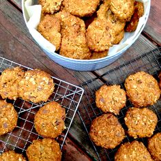 some muffins are cooling on a wire rack next to a bowl of oatmeal cookies