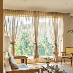 a living room filled with furniture next to a large window covered in white drapes