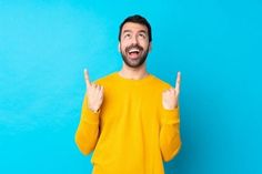 a man in a yellow sweater making the number one sign with his hands against a blue background