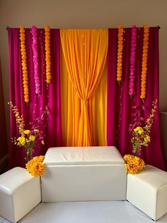 a white bench sitting in front of a red and yellow curtain with flowers on it