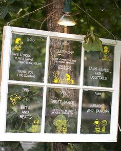 a sign hanging from the side of a tree in front of a window with writing on it