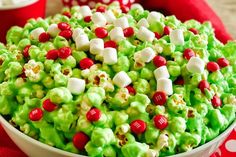 a white bowl filled with green and red candy popcorn covered in marshmallows