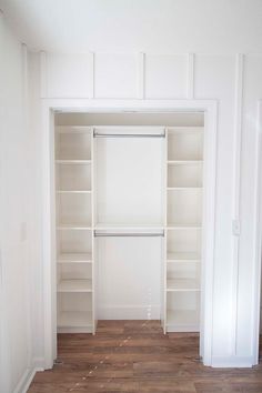 an empty closet with white walls and wooden floors