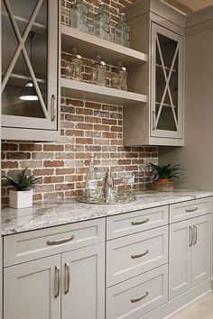 a kitchen with white cabinets and brick wall