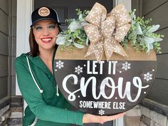 a woman holding a sign that says let it snow somewhere else