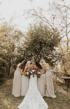 a group of bridesmaids standing in front of a tree with their backs to the camera