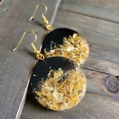 two black and gold earrings sitting on top of a wooden table