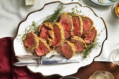 some meat is on a white plate with silverware