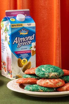 almond breeze cookies are stacked on a plate next to a carton of milk