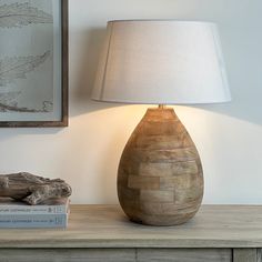 a wooden table with a lamp on top of it next to a painting and a book