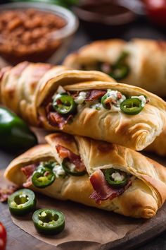 three croissants filled with bacon, cheese and jalapenos on a cutting board