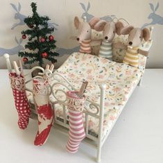 there are three mice on the bed next to christmas stockings and umbrellas in front of a small tree