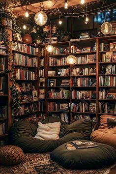 a living room filled with lots of books and lights hanging from the ceiling above it