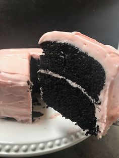 a slice of cake with pink frosting on a white plate next to a fork