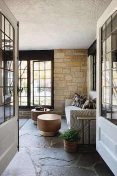 a living room with stone walls and flooring next to a door that has glass windows