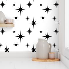 a white wall with black stars on it and a wooden shelf next to the wall