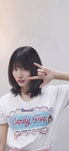 a young woman making the peace sign with her hand while standing in front of a white wall