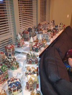 a child is sitting on a chair in front of a christmas display with small houses