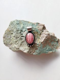 This adorable pendant is Navajo handmade handcrafted by Mary Spencer from Gallup New Mexico. Mary has used a beautiful piece of the Rhodochrosite stone, Rhodochrosite is found in a few different places including Peru, Montana and Mexico. The artist has set the beautiful stone into a sterling silver setting that has been oxidized to give it that old antique vibe. The bale on this piece is a decent size so a small or thicker chain will work. Please message me with any questions you may have. Handmade Pink Southwestern Jewelry, Southwestern Style Pink Jewelry Gift, Bohemian Rhodonite Jewelry With Natural Stones, Handmade Southwestern Style Oval Pendant Necklace, Handmade Southwestern Oval Pendant Necklace, Handmade Southwestern Necklace With Oval Pendant, Handmade Pink Oval Pendant Jewelry, Handmade Southwestern Jewelry For Healing, Gallup New Mexico