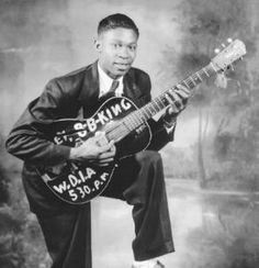 a man in a suit and tie holding a guitar