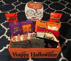 an orange box filled with halloween treats and candy bar wrappers on top of a bed