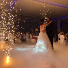 a bride and groom are dancing in the clouds at their wedding reception with sparklers