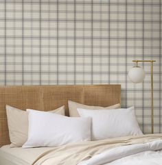 a bed with white pillows and plaid wallpaper