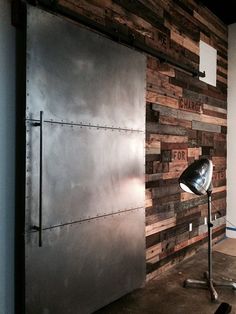 a metal door and some lights on a wall in a room with wood planks