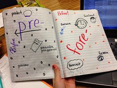 an open notebook with handwritten words and pictures on it, in front of a laptop