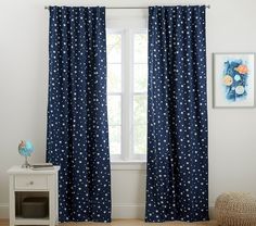 a blue curtain with white stars is hanging in front of a window, next to a small table and chair