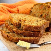 slices of banana bread on a cutting board with butter and orange towels in the background