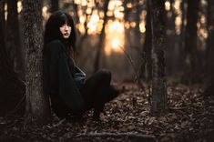 a woman is sitting in the woods with her legs crossed