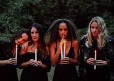 three women holding candles in front of their faces with one woman looking at the camera