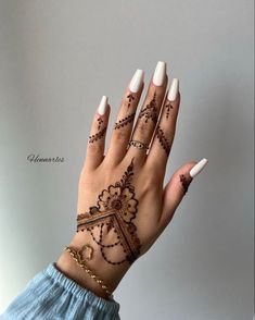 a woman's hand with henna tattoos and white nails on her left hand