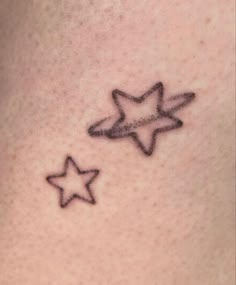 a small star tattoo on the back of a woman's neck, with two smaller stars behind it