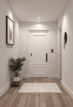 an empty hallway with a potted plant and two framed pictures on the wall next to it